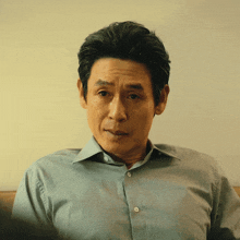 a man wearing a blue shirt is looking at the camera