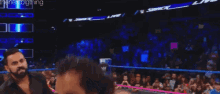 a man in red underwear is standing in a wrestling ring with his hands up .