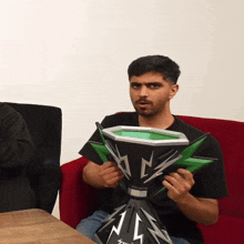 a man sitting on a red couch holding a trophy that says nlz