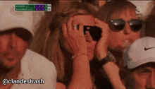 a woman wearing sunglasses is covering her eyes while watching a golf game with a scoreboard that says sinner on it