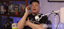 a man is giving a thumbs up in front of a microphone with dark web written on the bottom right