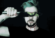 a man with green hair holds a knife over his face