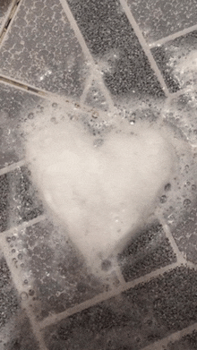 a heart shaped soap bubble is floating on a tile floor