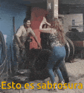 a man and a woman are standing next to a large tire with the words esto es sabrosa written above them