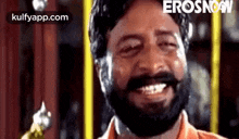 a man with a beard is smiling with his eyes closed in a room .