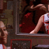 two cheerleaders are sitting in front of a bulletin board that has a yellow sticker that says " just do it "