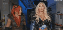 two female wrestlers are standing next to each other in a dark room .