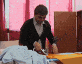 a man ironing clothes in front of a window