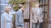 a man in a suit and tie is standing in front of a door talking to a woman and a man .