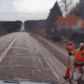a person holding a stop sign on the side of a road