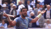 a man in a blue shirt is holding a tennis racquet up in the air