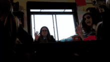 a group of girls are looking out a window and one of them is wearing glasses