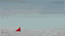 a man in a red suit is walking on a sandy beach