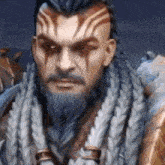 a man with a beard and braided hair is standing in front of a mountain in a video game .