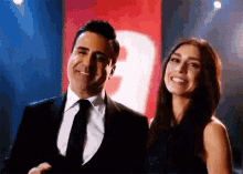 a man in a suit and tie is standing next to a woman in a black dress