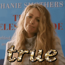 a woman stands in front of a sign that says " true "