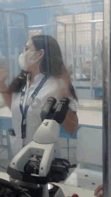 a woman looking through a microscope with a lanyard that says n on it