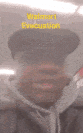 a man wearing a walmart evacuation hat is making a funny face .