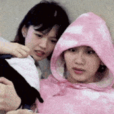 a woman in a pink tie dye hoodie is sitting next to another woman