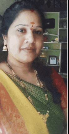 a woman wearing a green and yellow saree with a gold necklace