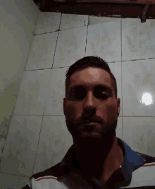 a man with a beard is taking a selfie in front of a tiled floor