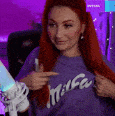 a woman with red hair is wearing a purple milka t-shirt