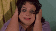a woman wearing a wig with black eyes and mascara on her face .