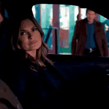 a woman is sitting in a car looking out the window at a man