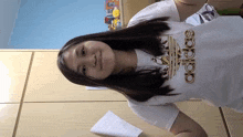 a woman wearing a white adidas shirt stands in front of a closet