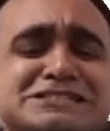 a man is making a funny face with his eyes closed .