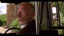 a man with a beard is sitting in the driver 's seat of a car .