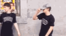 two boys are standing next to each other in front of a building .