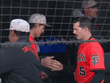 a baseball player wearing a red jersey with the number 5 on it