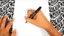 a person is drawing on a piece of paper with a black marker that says ' waterproof ' on it