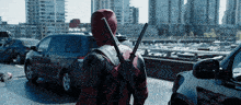 a man in a deadpool costume holds two swords
