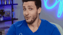 a man with a beard wearing a blue shirt with the letter a on it