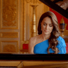 a woman in a blue dress is playing the piano