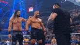 a group of wrestlers are standing in a ring talking to each other .
