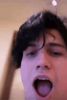 a close up of a young man 's face with his mouth open