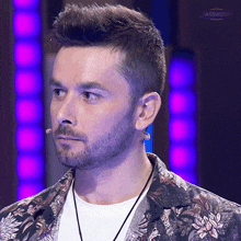 a man with a beard is wearing a floral shirt and a white shirt with a necklace around his neck