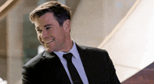 a man in a suit and tie is smiling and looking to the side