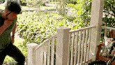 a man is standing on a porch next to a woman sitting on a bench .