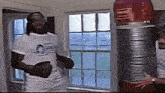 a man in a white shirt is standing next to a punching bag that says rlv