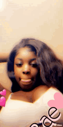 a woman with long hair is taking a selfie with a pink heart on her chest .