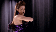 a woman in a purple sequined dress is singing