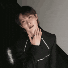 a man in a black jacket is holding his hand to his face