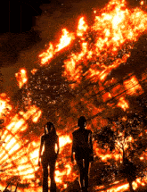 a couple standing in front of a large fire