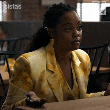 a woman sitting at a table with the word sistas on the bottom right