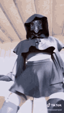 a woman wearing a gas mask and a hooded cape