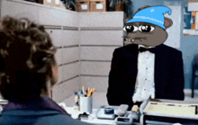 a man in a tuxedo and a blue hat looks at another man